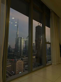 an empty room with large windows looking out at the cityscape and skyscrapers