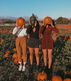 three young women holding pumpkins in their hands