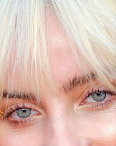 a close up of a person with blonde hair and blue eyes smiling at the camera