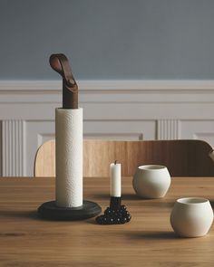 a wooden table topped with two white vases next to a roll of toilet paper