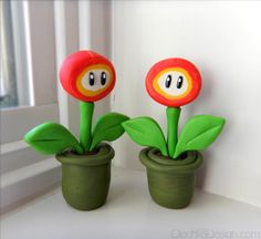 two plastic flowers sitting on top of a window sill in front of a white wall