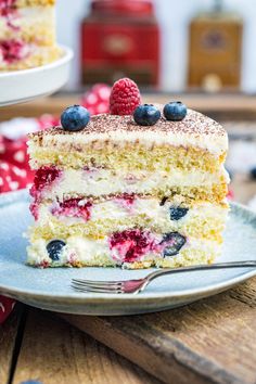 a piece of cake on a plate with blueberries and raspberries