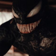 a close up shot of the face and mouth of an evil looking spider - man