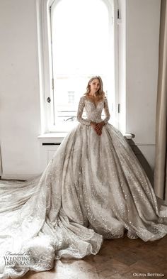 a woman in a wedding dress standing by a window