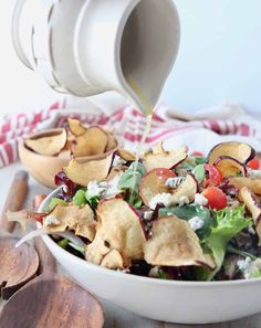 a white bowl filled with salad and chips being drizzled on top of it