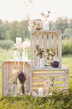 an assortment of vases, candles and flowers are on display in front of a wooden crate