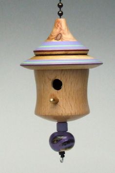 a wooden birdhouse with a purple and blue decoration hanging from it's side