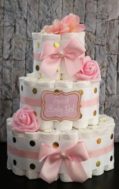 a three tiered baby shower cake with pink and gold polka dots on the bottom