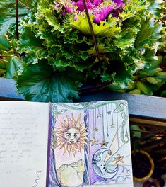 an open book sitting on top of a table next to a vase filled with flowers