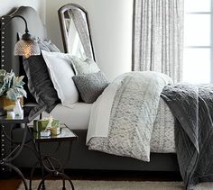 a bedroom with a bed, mirror and table in front of the window is shown