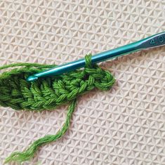 a green crochet hook laying on top of a white surface