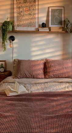 the bed is made up with pink sheets and pillows, along with pictures on the wall