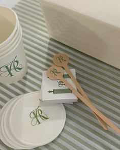 paper plates and wooden spoons sitting on top of a striped table cloth next to a cup