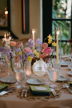 the table is set with flowers, candles and place settings for an elegant dinner party