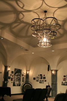 an empty room with chairs and pictures on the wall behind it, along with a chandelier hanging from the ceiling