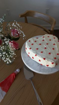 a heart shaped cake sitting on top of a table next to a vase with flowers