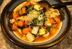 a bowl filled with soup and vegetables on top of a table