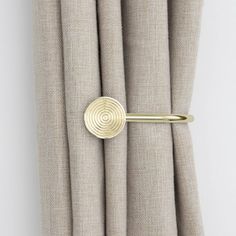 a curtain with a gold ring on top of it next to some beige linens