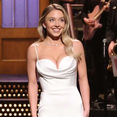 a woman in a white dress standing next to a microphone