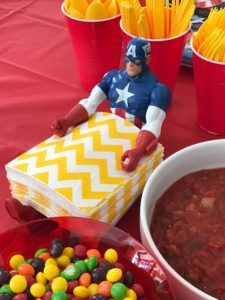 a table topped with red cups filled with candy and other items next to a bowl of chili