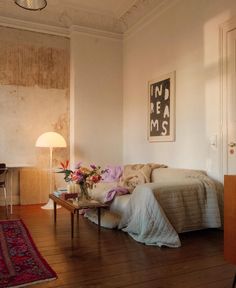 a bed sitting in a bedroom on top of a hard wood floor next to a table