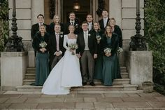 a bride and groom with their bridal party in front of the entrance to an old building