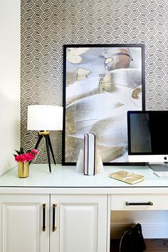 a white desk with a computer monitor, keyboard and mouse next to a painting on the wall