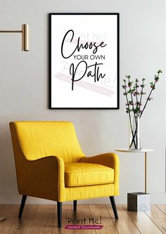 a yellow chair sitting in front of a white wall next to a vase with flowers