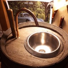 a metal sink sitting on top of a wooden barrel next to a magazine with an image of a car in the background