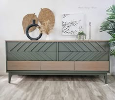 a green dresser sitting on top of a wooden floor next to a potted plant