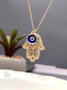 Beautifully CZ embedded gold hamsa hand pendant with Blue evil eye charm on 18K gold filled chain. HAMSA HAND Depicting the open right hand, an image recognized and used as a SIGN OF PROTECTION in many societies throughout history, the HAMSA is believed to provide defense against the evil eye. *Hamsa Hand Charm measures 20mm x 17mm ---------------------------------------- ++ FEATURES ++ - High quality Gold/RG/Rhodium plated over Brass Hamsa charm - CZ - Double sided Glass evil eye charm with gol Evil Eye Layered Necklace, Evil Eye Necklaces, Blue Gold Plated Charm Necklace As Gift, Gold Plated Evil Eye Charm Necklace Gift, Nazar Jewelry, Evil Eye Jewelry Necklace, Gold Evil Eye Jewelry, Blue Evil Eye Necklace, Hamsa Hand Jewelry