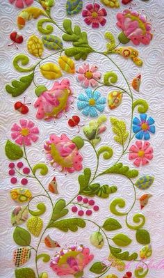 a quilted wall hanging with flowers and leaves on it