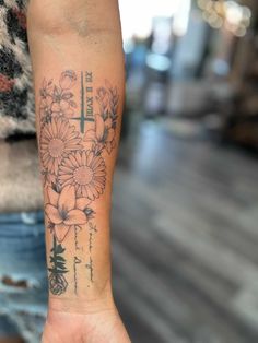 a woman's arm with a cross and flowers tattooed on the side of it