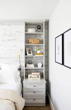 a bedroom with a bed, nightstand and bookcase in white wood paneled walls