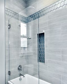 a white bath tub sitting inside of a bathroom next to a shower head and window