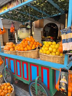 an outdoor fruit stand with oranges, lemons and other fruits in baskets on wheels