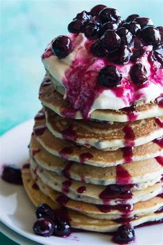 a stack of pancakes topped with whipped cream and blueberries on top of each other