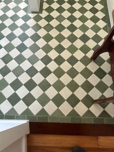 a bird statue sitting on top of a green and white checkered tile floor next to a sink