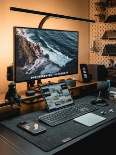 a desk with a laptop, keyboard and mouse on it in front of a monitor