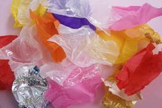 there are many different colored pieces of tissue paper on the table, and one is wrapped in plastic