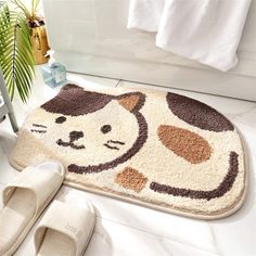 a bathroom rug with a cartoon cat on it and slippers next to the bathtub