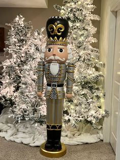 a nutcracker standing in front of a christmas tree with white and gold decorations