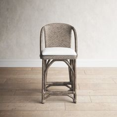 a wicker chair sitting on top of a hard wood floor next to a white wall