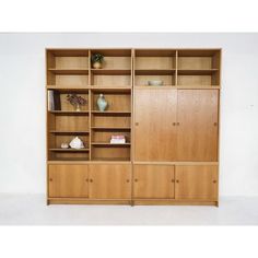 a wooden bookcase with two doors and shelves on each side, in front of a white wall