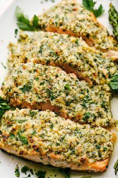 grilled salmon topped with herbs and parsley on a white plate next to asparagus