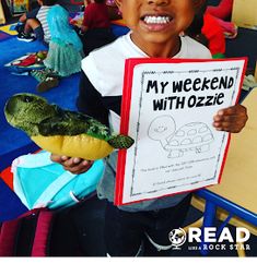 a young boy holding up a sign with an alligator on it