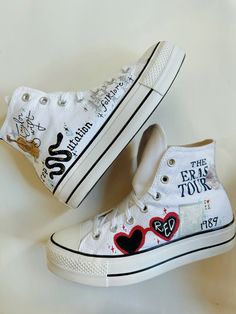 two pairs of white sneakers with hearts and words painted on them