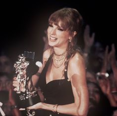 a woman holding an award in front of a crowd