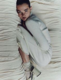 a woman laying on top of a bed covered in white sheets