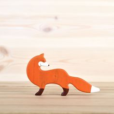 an orange wooden toy fox standing on top of a wooden floor